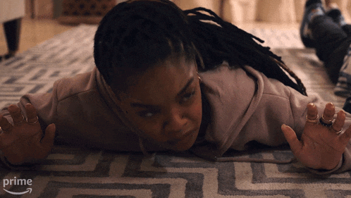 a woman with dreadlocks is laying on a rug that says prime on the bottom right