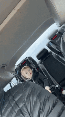 a baby is sitting in a graco car seat in the back seat of a car