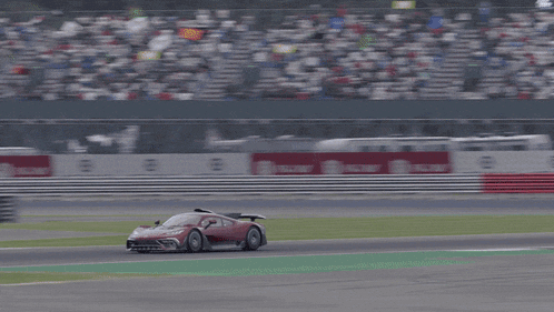 a red race car is driving on a track with a sign in the background that says ' coca-cola '