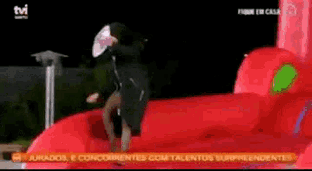 a person is jumping on a bouncy castle with a tv logo in the background