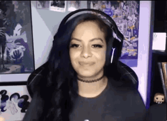 a woman wearing headphones and a choker smiles