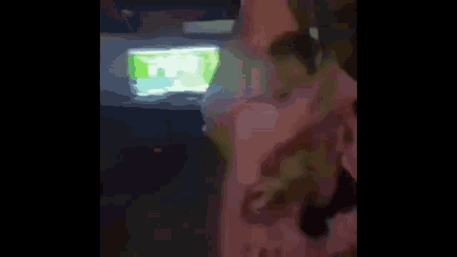 a blurry picture of a person standing in front of a tv screen .