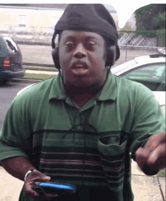 a man wearing headphones and a black hat holds a cellphone