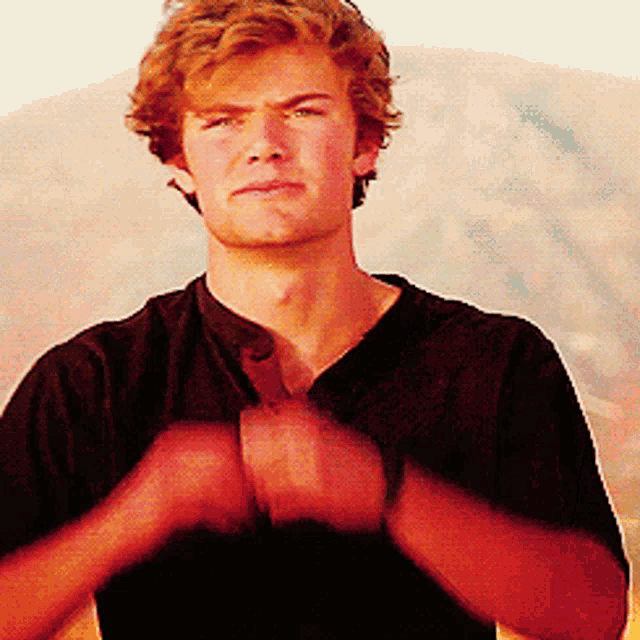 a young man in a black shirt is making a face