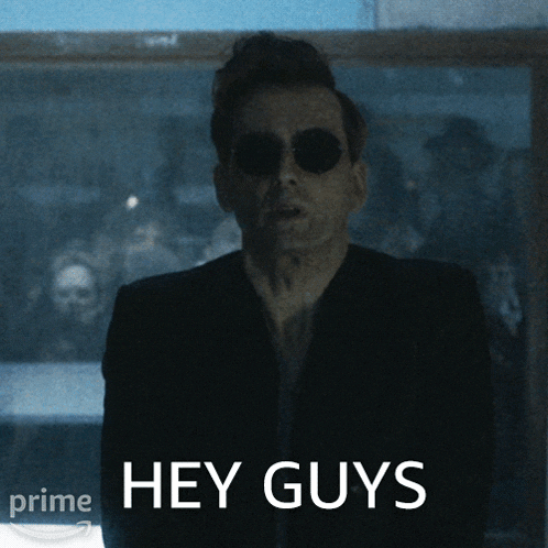 a man wearing sunglasses says hey guys in front of a window