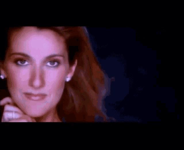 a close up of a woman 's face with a ring on her finger and earrings .
