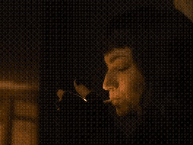 a woman lighting a cigarette in the dark with her eyes closed