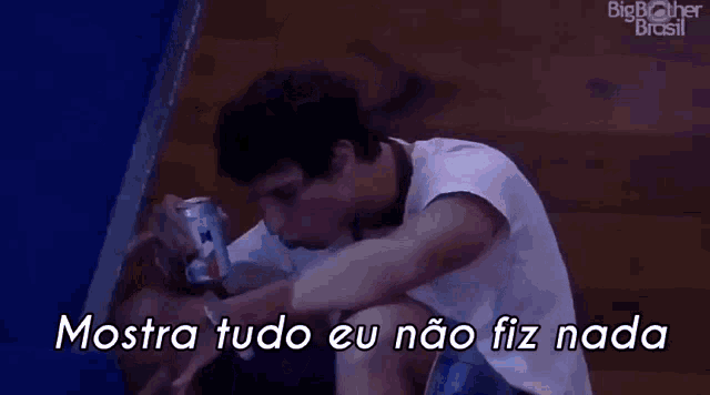 a man is sitting on the floor with a can of beer in his hand and a caption that says mostra tudo eu não fiz nada