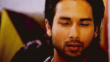 a man with a beard is looking down with his eyes closed .