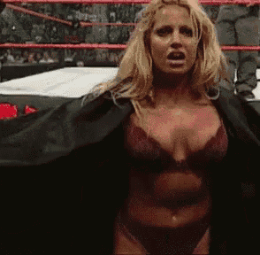 a woman in lingerie is standing in a wrestling ring wearing a black robe .