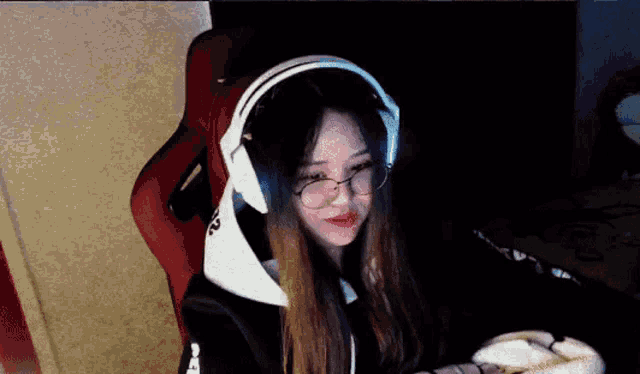 a girl is wearing headphones and glasses while sitting in a chair .
