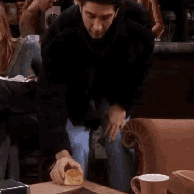 a man is sitting at a table with a plate of food on it and eating pizza .