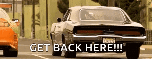 a car is driving down a street with the words `` get back here '' written on the bottom of it .