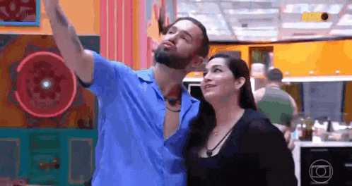 a man and a woman are standing next to each other in a room and taking a selfie .