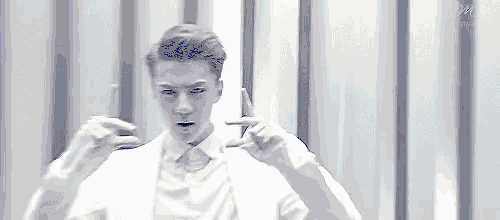 a man in a white shirt and tie is making a funny face and making a peace sign with his hands .