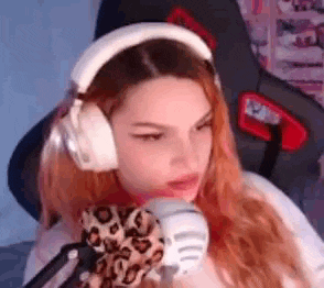 a girl wearing headphones and a scarf is sitting in front of a microphone .