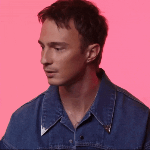 a man wearing a blue denim shirt and a necklace