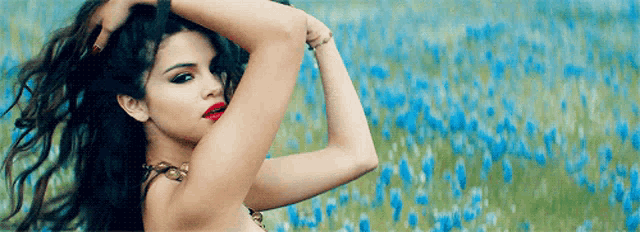 a woman with red lipstick is standing in a field of flowers .
