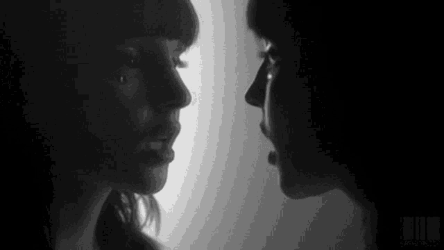 two women are kissing in a black and white photo .