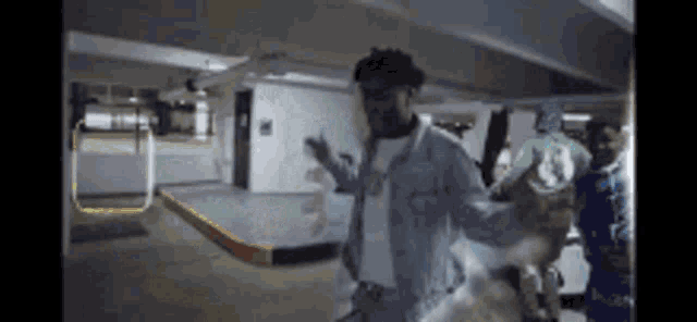 a man in a denim jacket is dancing in a parking garage with other people .