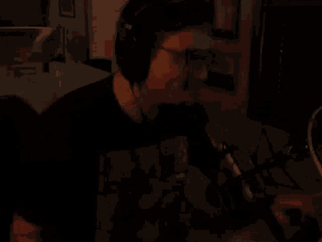 a man wearing headphones and glasses is smiling while playing a video game .