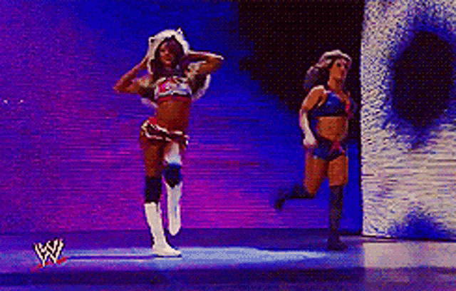 two women are dancing in front of a wrestling logo