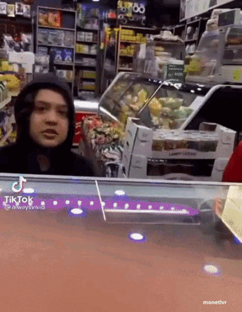 a man in a hooded jacket is behind a counter in a store