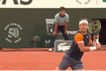 a man holding a tennis racquet on a court with a bnp paribas sign behind him
