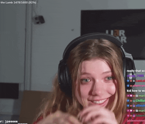 a girl wearing headphones is smiling in front of a sign that says the lamb 1478/1600