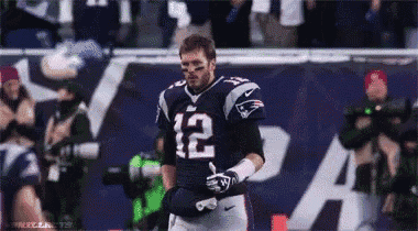 a football player with the number 12 on his jersey stands on the field