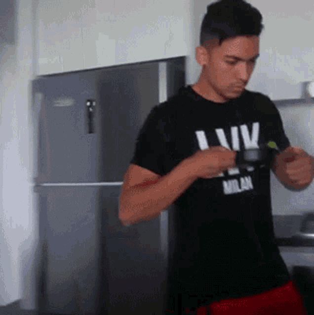 a man wearing a milan shirt is standing in a kitchen