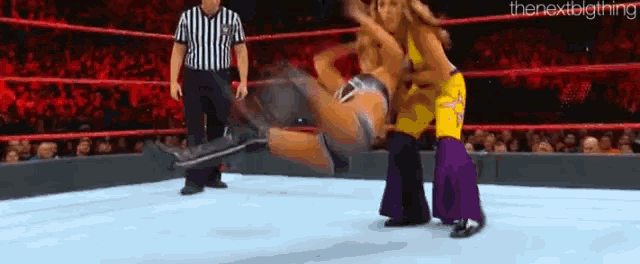 two women are wrestling in a wrestling ring while a referee looks on .