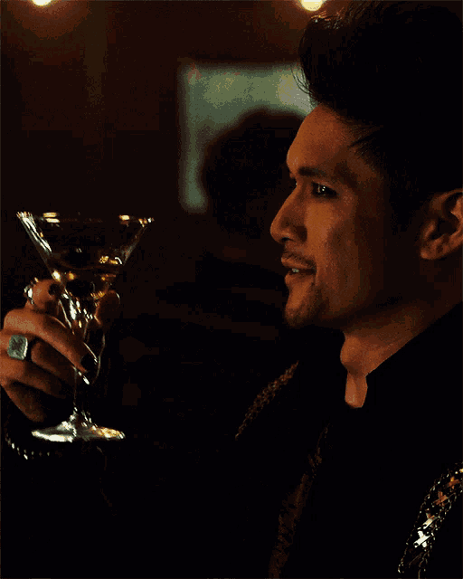 a man is holding a martini glass in his right hand