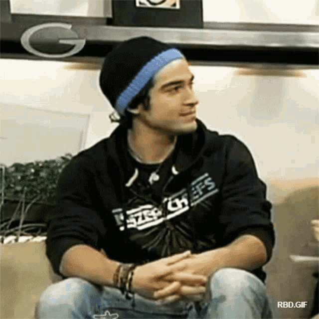 a man wearing a black sweatshirt that says step on life sits on a couch