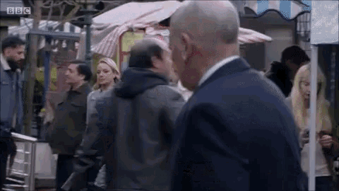 a man in a suit is standing in front of a crowd of people in a street .