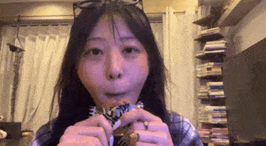 a woman is eating a sandwich in a living room while wearing glasses .