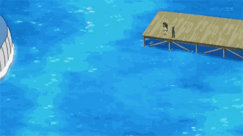 a large blue whale is floating in the ocean next to a wooden pier .