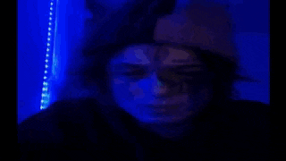 a close up of a person 's face with green and blue lights behind them .