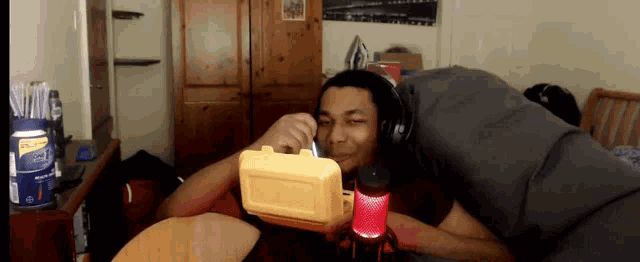 a man wearing headphones is laying on a bed next to a microphone with a can of sprite in the background