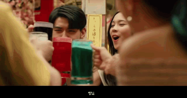 a group of people are toasting with glasses of different colored liquids .