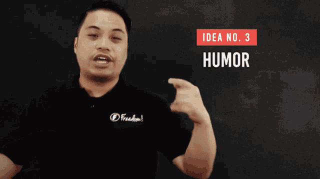 a man wearing a black shirt that says freedom is pointing at the word humor