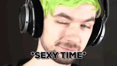 a man with green hair and a beard wearing headphones says sexy time .