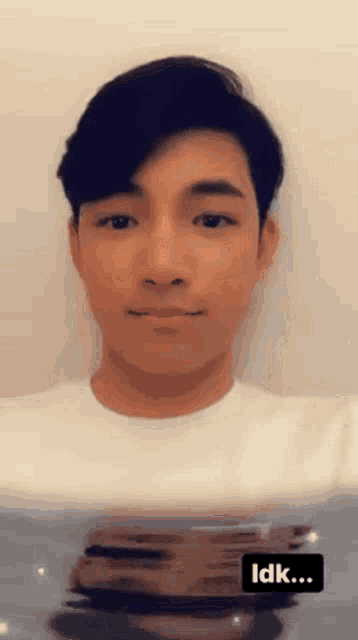 a young man in a white shirt with a black idk sticker