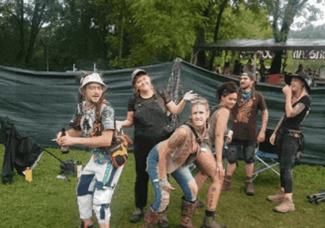 a group of people posing for a picture in front of a fence with a sign that says ' wine ' on it