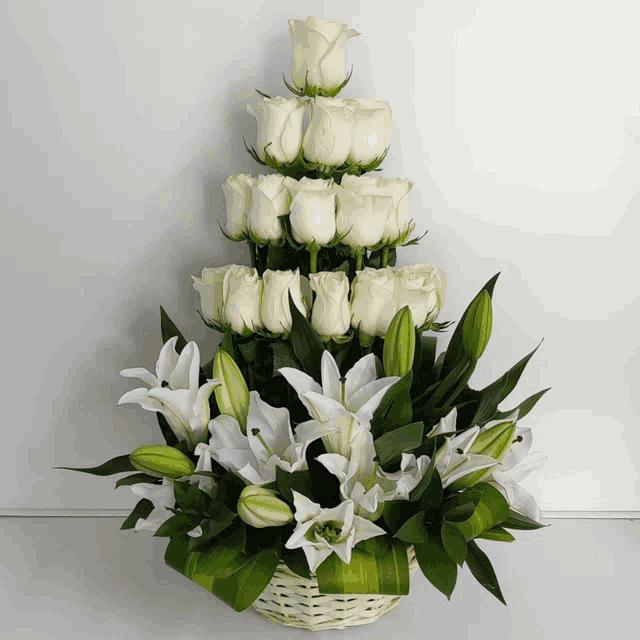 a basket filled with white roses and lilies on a table