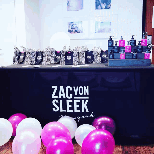 a table with pink and white balloons and a sign that says zac von sleek new york