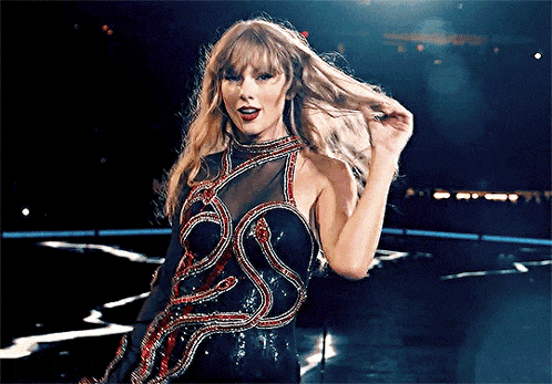 a woman in a black dress is standing on a stage holding her hair