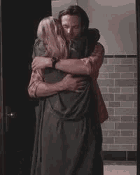 a man and a woman are hugging each other in a room .