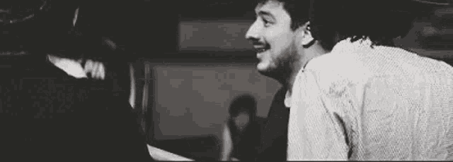 a black and white photo of a man standing next to a woman in a room .