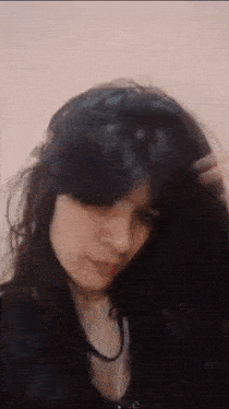 a close up of a woman with long black hair holding her hair .